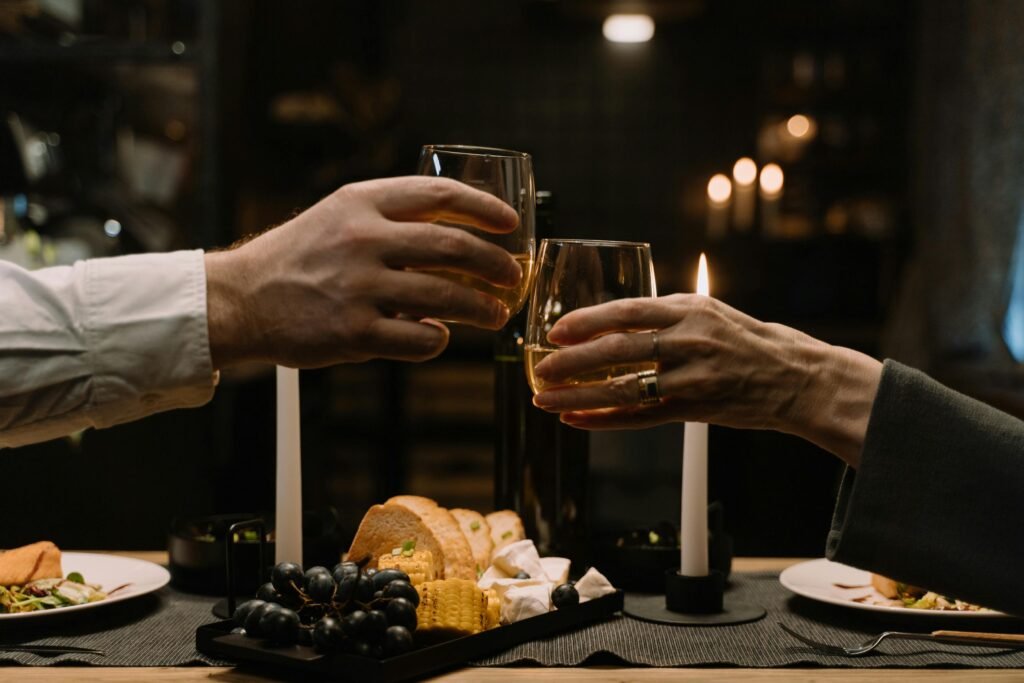 Intimate dinner setting with wine glasses, candles, and a variety of foods for a romantic evening.